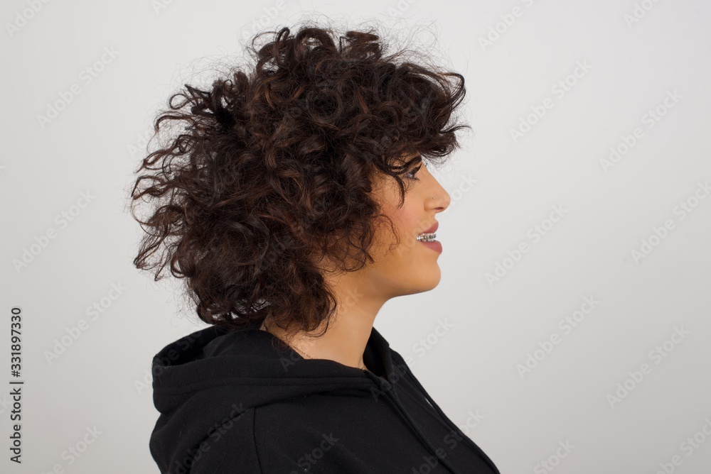 Profile of smiling woman with healthy pure skin, has contemplative expression, ready to have outdoor walk, isolated over white studio wall with copy space Profile of smiling woman with healthy pure skin, has contemplative expression, ready to have outdoor walk, isolated over white studio wall with copy space
