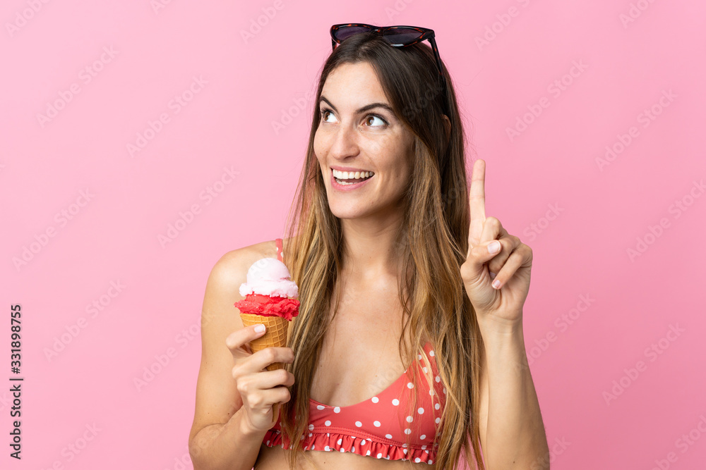 Young caucasian woman holding an ice cream isolated on pink background intending to realizes the solution while lifting a finger up Young caucasian woman holding an ice cream isolated on pink background intending to realizes the solution while lifting a finger up