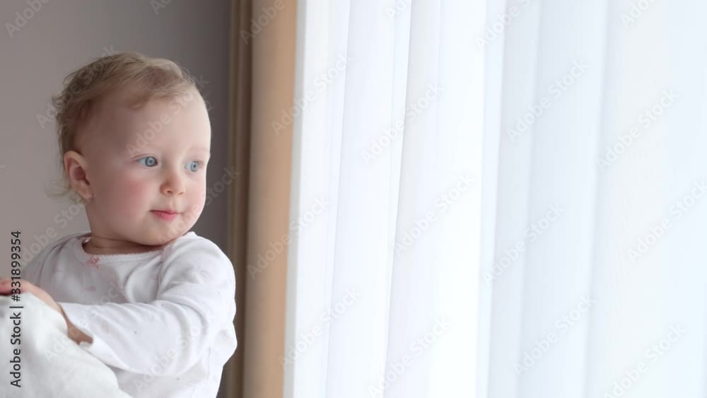 A little girl in her mother’s arms near the window. Slow motion, 4K video. A little girl in her mother’s arms near the window. Slow motion, 4K video.