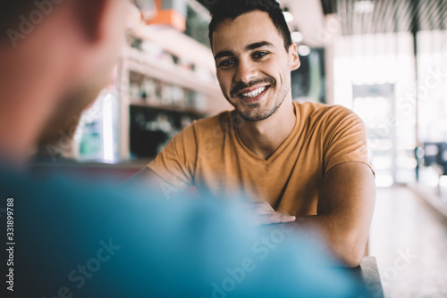 Cheerful young male friends having meeting in cafe