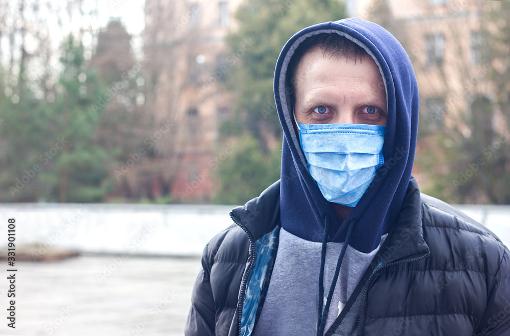 A young man in a mask to protect against coronovirus, flu and other diseases, also protection against allergies. City air pollution concept. COVID-19 Pandemic Coronavirus, Self-isolation and Quarant A young man in a mask to protect against coronovirus, flu and other diseases, also protection against allergies. City air pollution concept. COVID-19 Pandemic Coronavirus, Self-isolation and Quarant