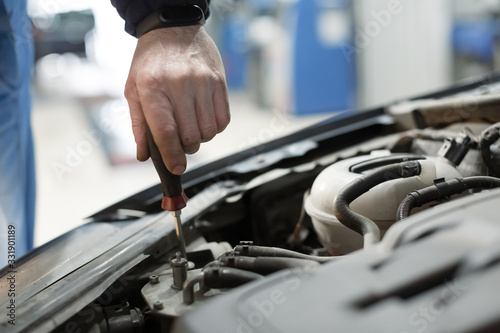 Adjusting the headlights on the car by mechanics hand in a garage. close up