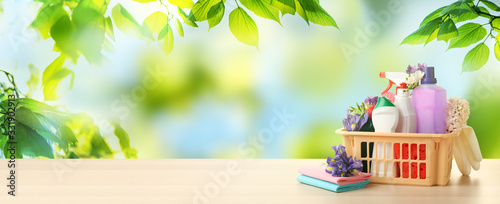 Tableau sur toile Plastic basket with different detergents on wooden table, space for text