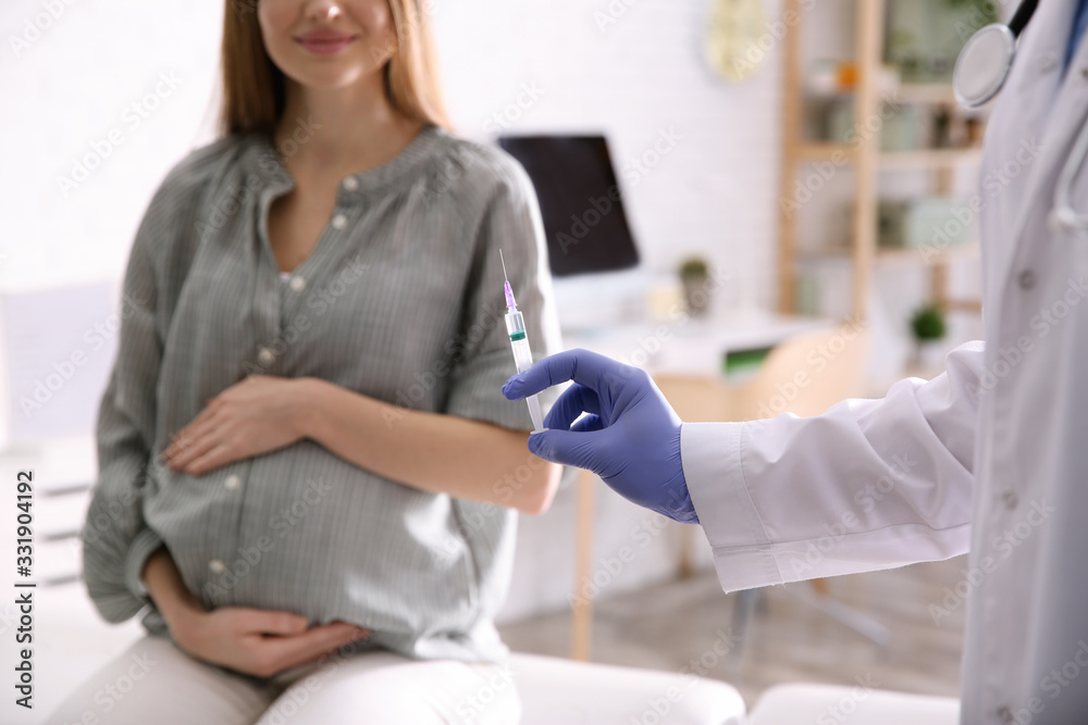 Doctor giving injection to pregnant woman in hospital, closeup. Vaccination concept Doctor giving injection to pregnant woman in hospital, closeup. Vaccination concept
