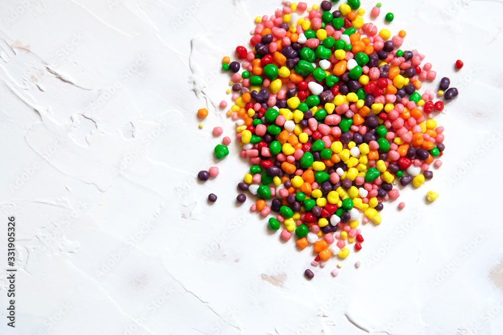 Rainbow colored candy sprinkled on a white background