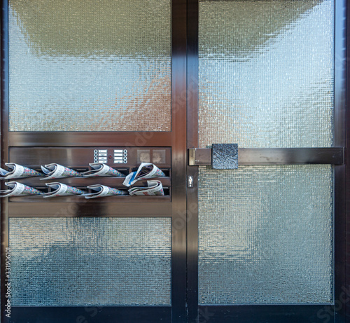 glass door with newspapers in mailboxes closeup