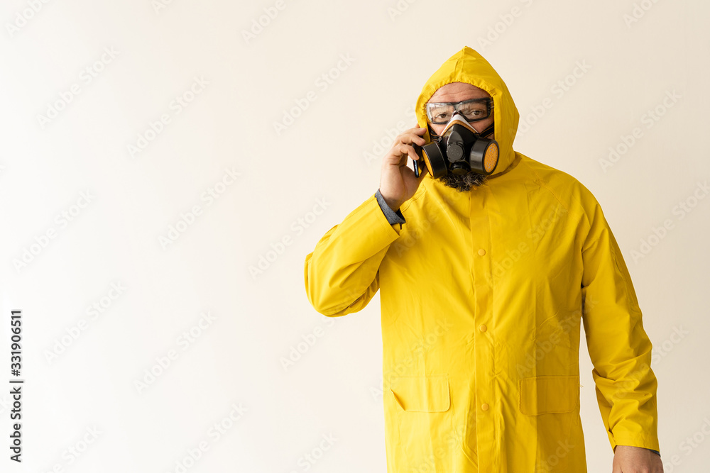 a man dressed in a yellow protective suit communicates on a cell phone. a man dressed in a yellow protective suit communicates on a cell phone.
