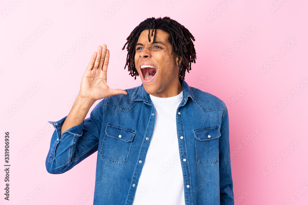 Young African American man with jean shirt over isolated pink background shouting with mouth wide open Young African American man with jean shirt over isolated pink background shouting with mouth wide open