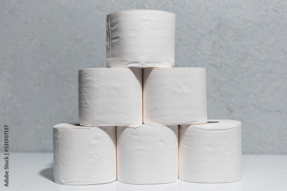 Close-up of toilet paper rolls on white table, background of textured wall grey of color. Close-up of toilet paper rolls on white table, background of textured wall grey of color.