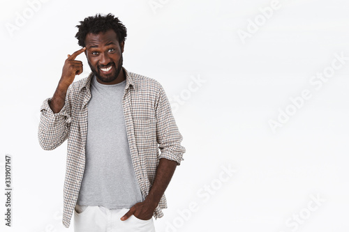 Think about it. Guy insist you should make choices wisely. Attractive smiling, happy african-american man grinning, pointing at temple or brain and gazing camera, hear clever advice photo