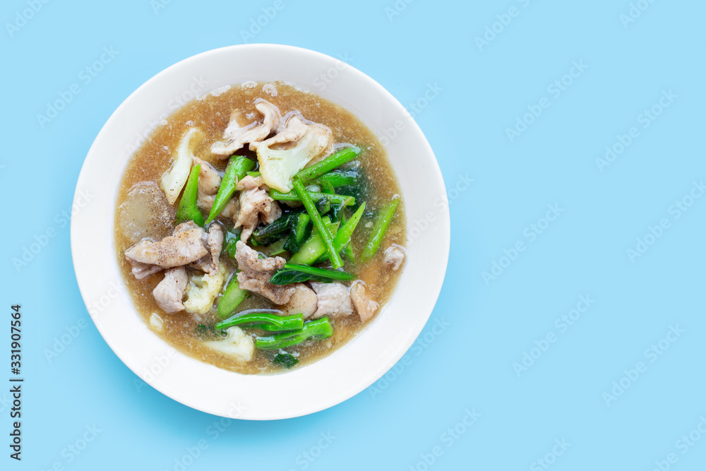 Fried noodle with pork and chinese broccol, cauliflower in white dish on blue background. Fried noodle with pork and chinese broccol, cauliflower in white dish on blue background.