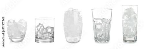 Set of different glasses with ice cubes on white background photo