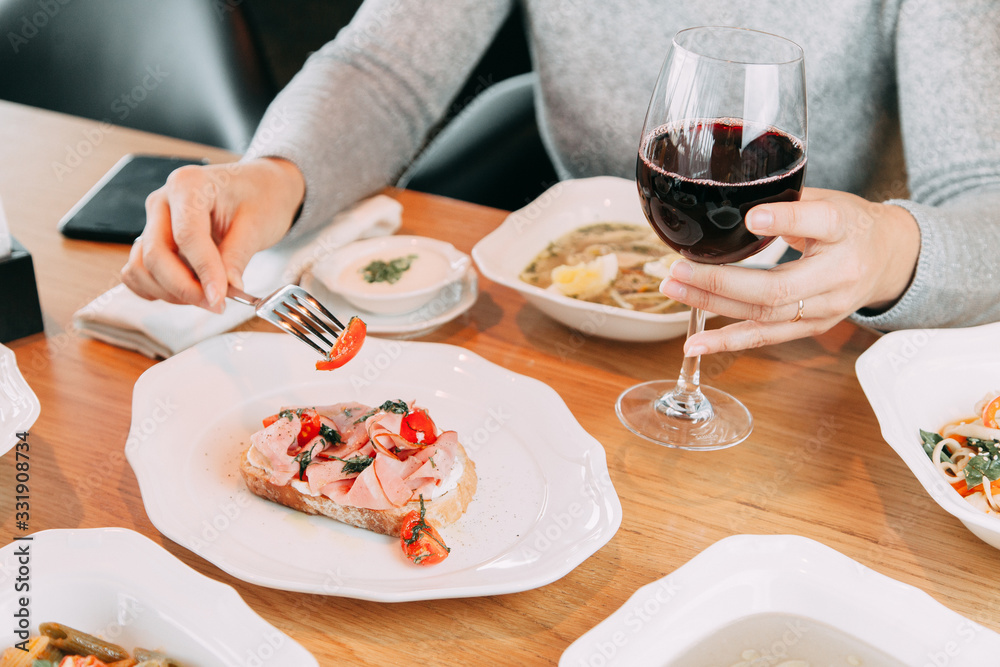 Restaurant dish on the menu with wine. The girl is eating bruschetta with bacon and tomato. Restaurant dish on the menu with wine. The girl is eating bruschetta with bacon and tomato.