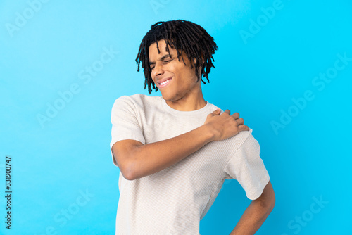 Young African American man over isolated blue background suffering from pain in shoulder for having made an effort