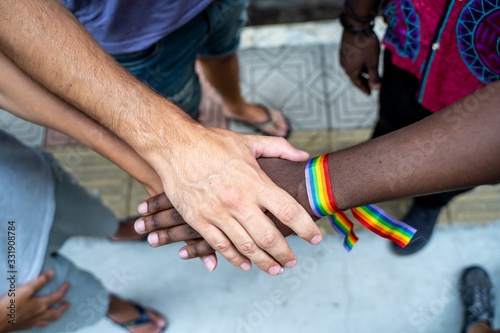 Detail of a group of hands from different ethnic groups with an lgtb flag