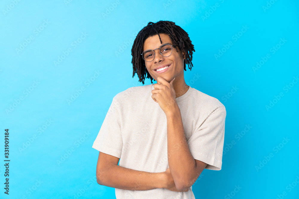 Young African American man over isolated blue background with glasses and smiling Young African American man over isolated blue background with glasses and smiling