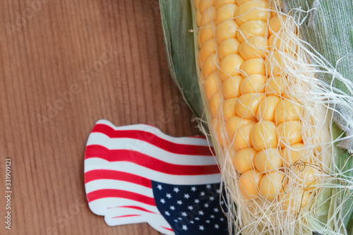 Obraz na płótnie Corn on the cob on the wooden floor with small United State of America flag made from paper w salonie