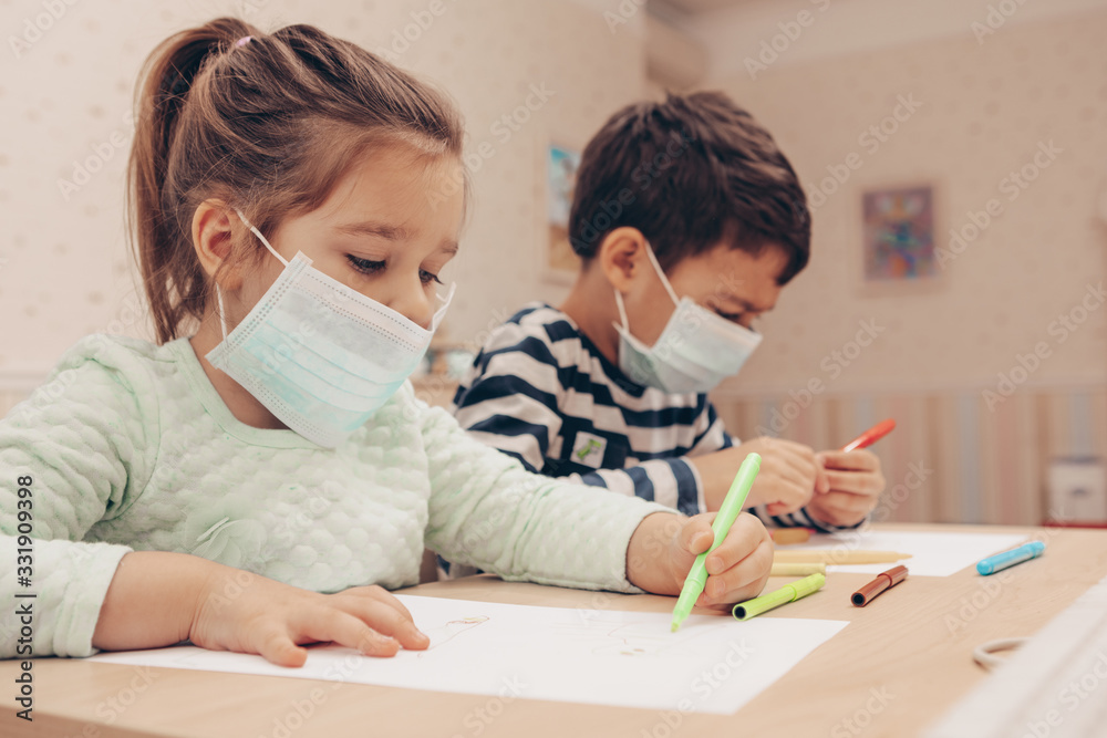 Cute children boy and girl in medical mask is sitting at home in quarantine. Сhildren play constructor after disinfection hands. Entertainment for the children during quarantine. Self isolation. Cute children boy and girl in medical mask is sitting at home in quarantine. Сhildren play constructor after disinfection hands. Entertainment for the children during quarantine. Self isolation.