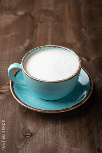 coffee with milk in a ceramic blue cup on a wooden background. Place for text, top view.