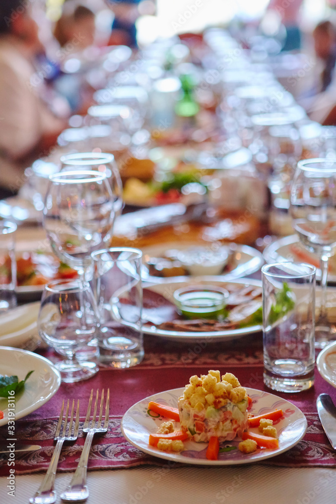 A group of people at a long table with food. The concept for the joint celebration of memorable dates or holidays A group of people at a long table with food. The concept for the joint celebration of memorable dates or holidays