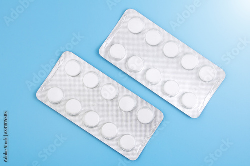 Blister with white tablets is isolated on a blue background. The concept of medicine, drugs, painkillers. Copy space