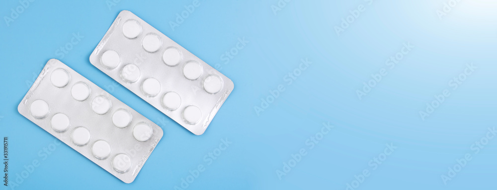 Blister with white pills isolated on a blue background. The concept of medicine, drugs, painkillers. Banner. Copy space