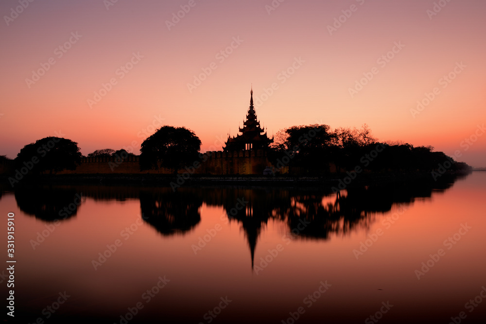 Night view to the silhouettes of the  Fort or Royal Palace in Mandalay, Myanmar (Burma) with red sunset sky