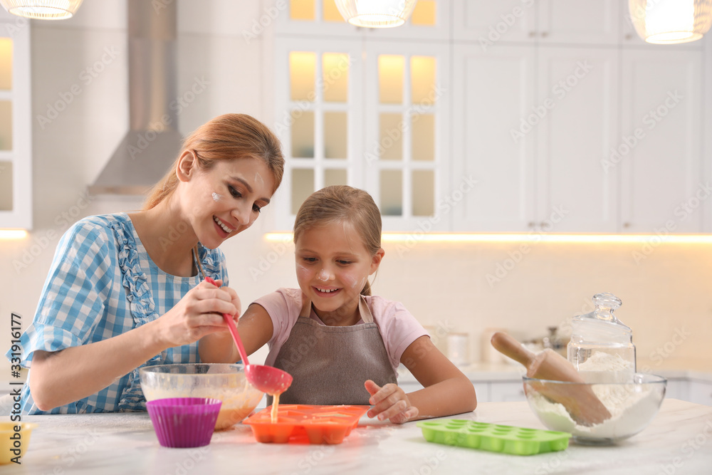 Mother and daughter making cupcakes together in kitchen