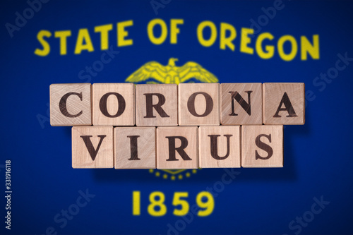 Flag of the state of Oregon with wooden cubes spelling coronavirus on it. 2019 - 2020 Novel Coronavirus (2019-nCoV) concept, for an outbreak occurs in Oregon. © bekulnis
