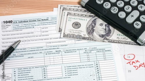 US 1040 tax return form with 100 usd dollar bills and calculator
