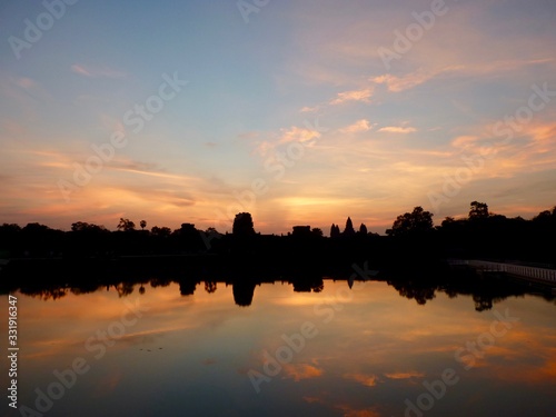 Angkor Wat during sunrise with pink clouds, shadows before lake with reflections, ruins of Angkor, Cambodia