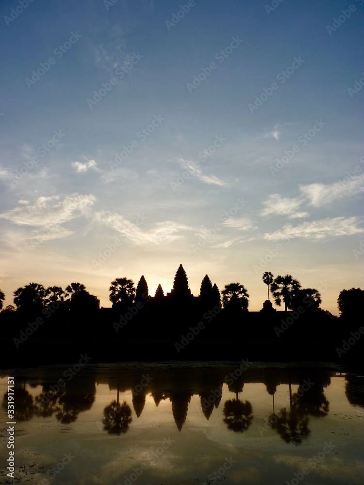 Obraz premium Angkor Wat during sunrise with clouds, shadow Silhouette before lake with reflections, ruins of Angkor, Cambodia