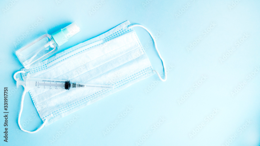 Antiseptic, medical mask and syringe on a blue background. Prevention, protection and treatment against viruses. Healthcare and medicine. Coronavirus, covid -19. Antiseptic, medical mask and syringe on a blue background. Prevention, protection and treatment against viruses. Healthcare and medicine. Coronavirus, covid -19.