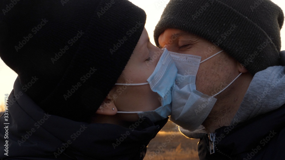 Young Couple Wearing Protective Face Masks And Kissing Outdoors. Virus Spread Prevention And People Concept. Young Couple Wearing Protective Face Masks And Kissing Outdoors. Virus Spread Prevention And People Concept.