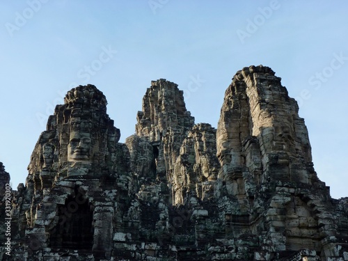 Ruins of Angkor, face towers of Bayon temple against blue sky, Angkor Wat, Cambodia