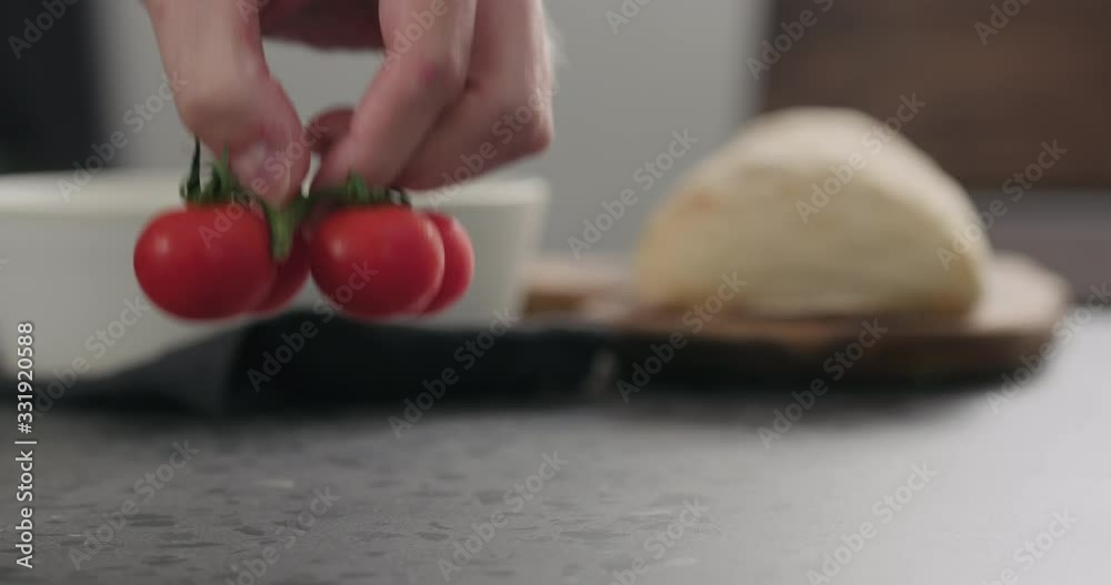 Slow motion man hand put cherry tomatoes branch on conrete countertop Slow motion man hand put cherry tomatoes branch on conrete countertop