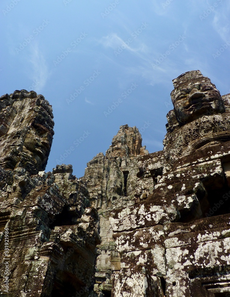 Ruins of Angkor, face tower of Bayon temple against blue sky, Angkor Wat, Cambodia