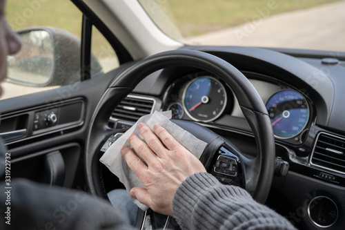 Man cleaning steering wheel of a car using antivirus antibacterial wet wipe (napkin) for protect himself from bacteria and virus.