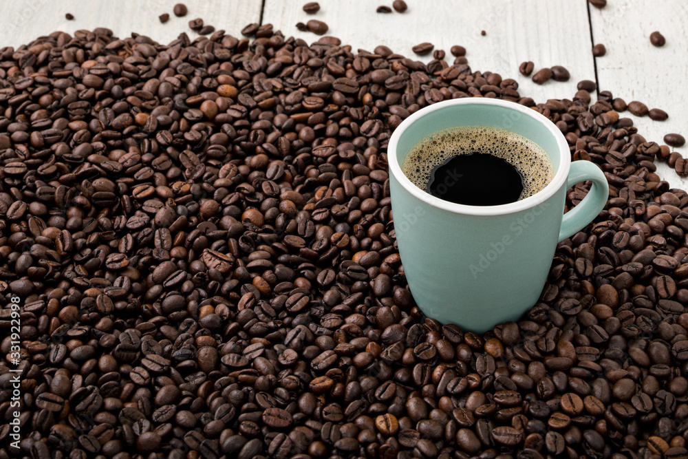 Fresh cup of coffee surrounded by freshly roasted Arabica beans on wooden background. Fresh cup of coffee surrounded by freshly roasted Arabica beans on wooden background.