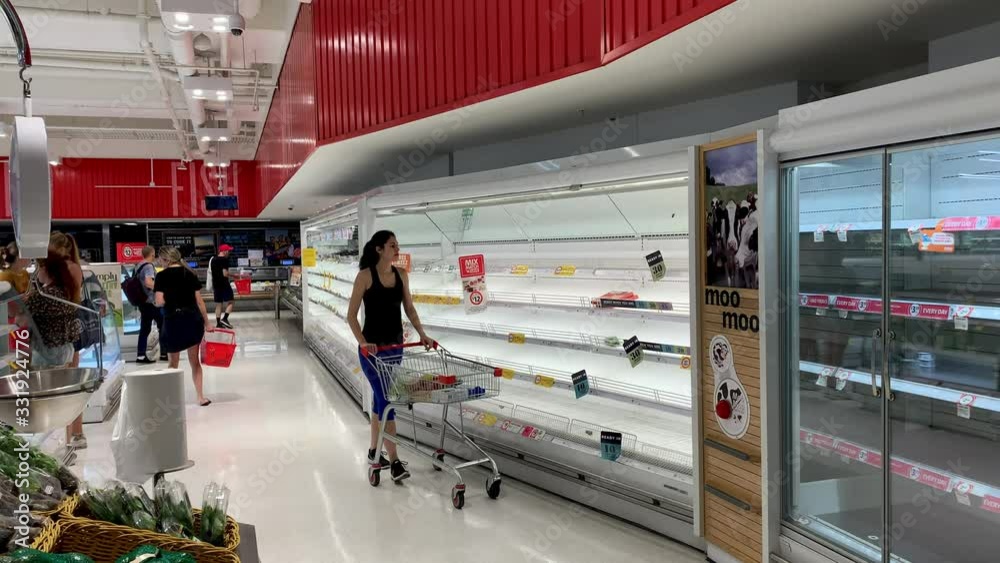 A shopper in Australia passes empty supermarket shelves during coronavirus (COVID-19) panic buying.