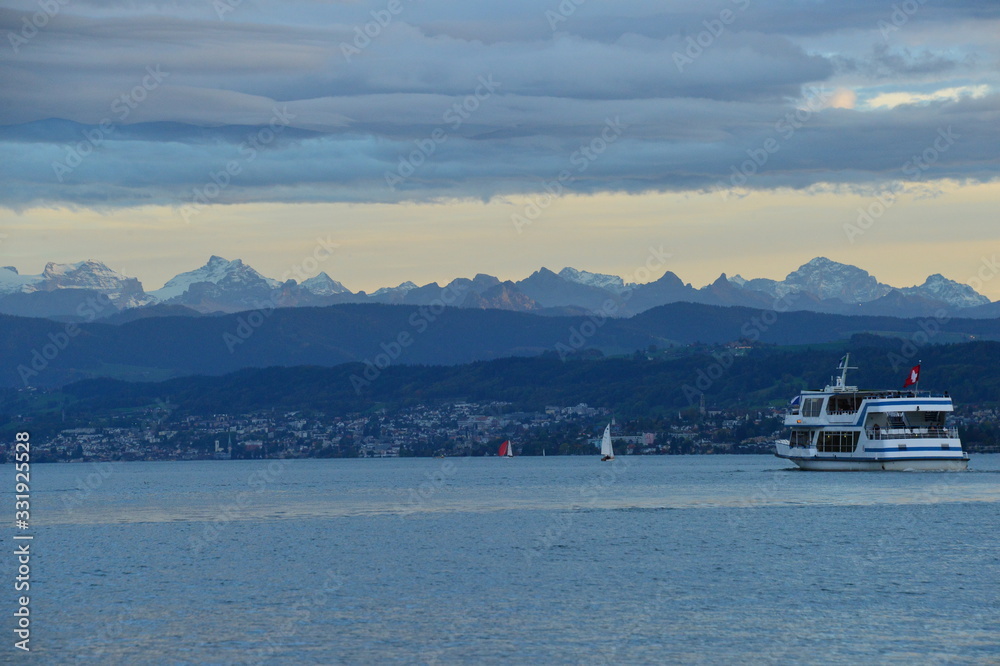 zurichsee with course boat and the alps in the evening mood