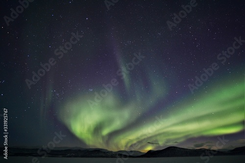 dancing green northern lights in the night sky over a mountain range in lapland finland © Ben T.
