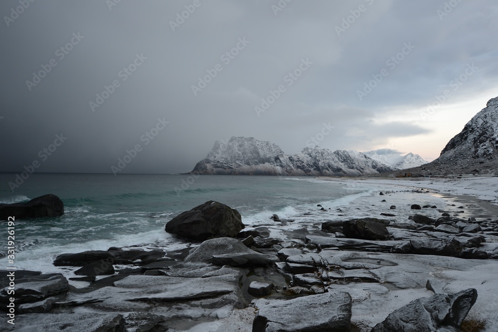 rain in a bay in norway in coordination with stones in the foreground