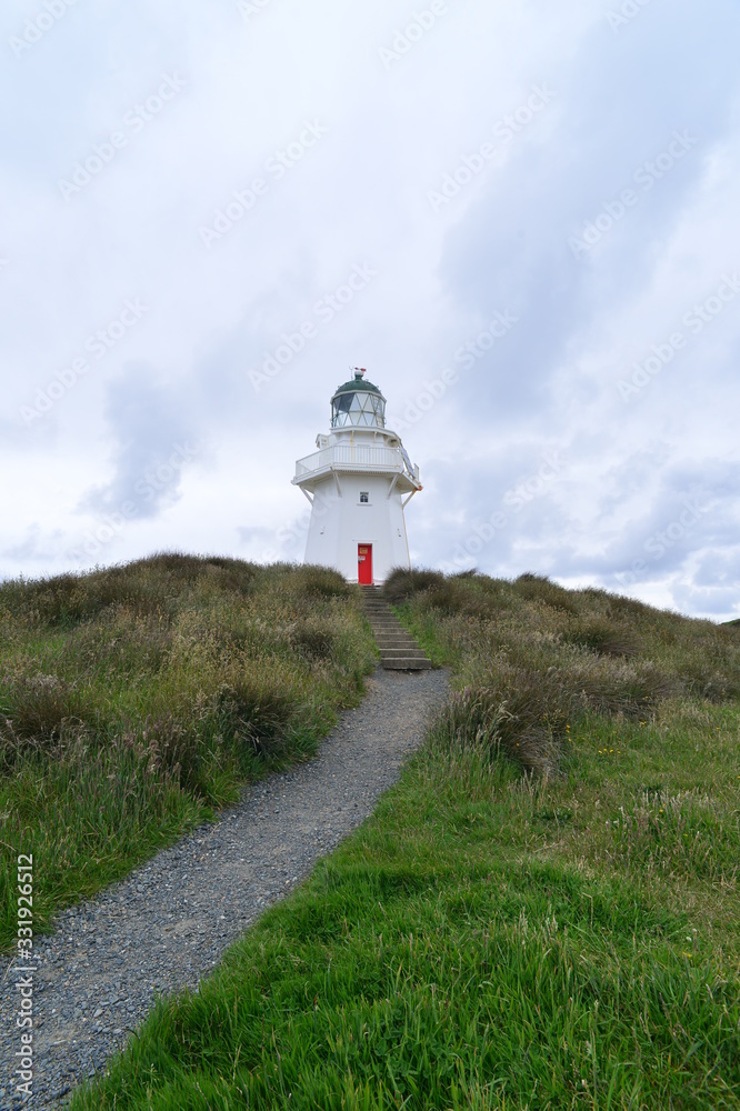 white lighthouse with red door in new zealand