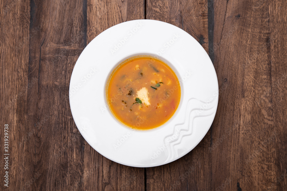 A plate of Minestrone soup in a white plate on a wooden table. Traditional Italian food, restaurant menu concept. A plate of Minestrone soup in a white plate on a wooden table. Traditional Italian food, restaurant menu concept.