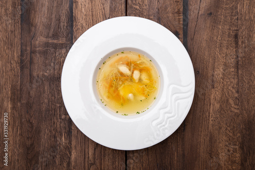 Chicken consomme with dumplings . Chicken broth with chicken fillet dumplings and quail egg. Healthy dietary tasty food, homemade meals. A plate of Chicken broth. Top view.