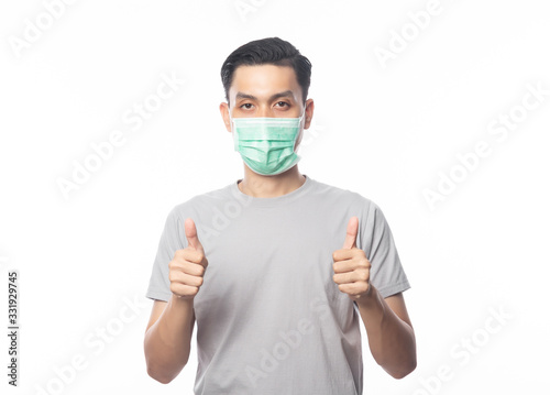 Young Asian Man wearing hygienic mask and showing thumbs up to prevent infection, 2019-nCoV or coronavirus. Airborne respiratory illness such as pm 2.5 fighting and flu isolated on white background.
