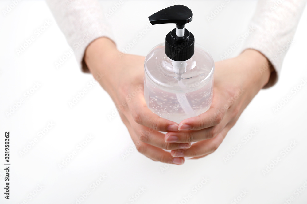 Hand holding a bottle of hand sanitizer gel on light background Hand holding a bottle of hand sanitizer gel on light background