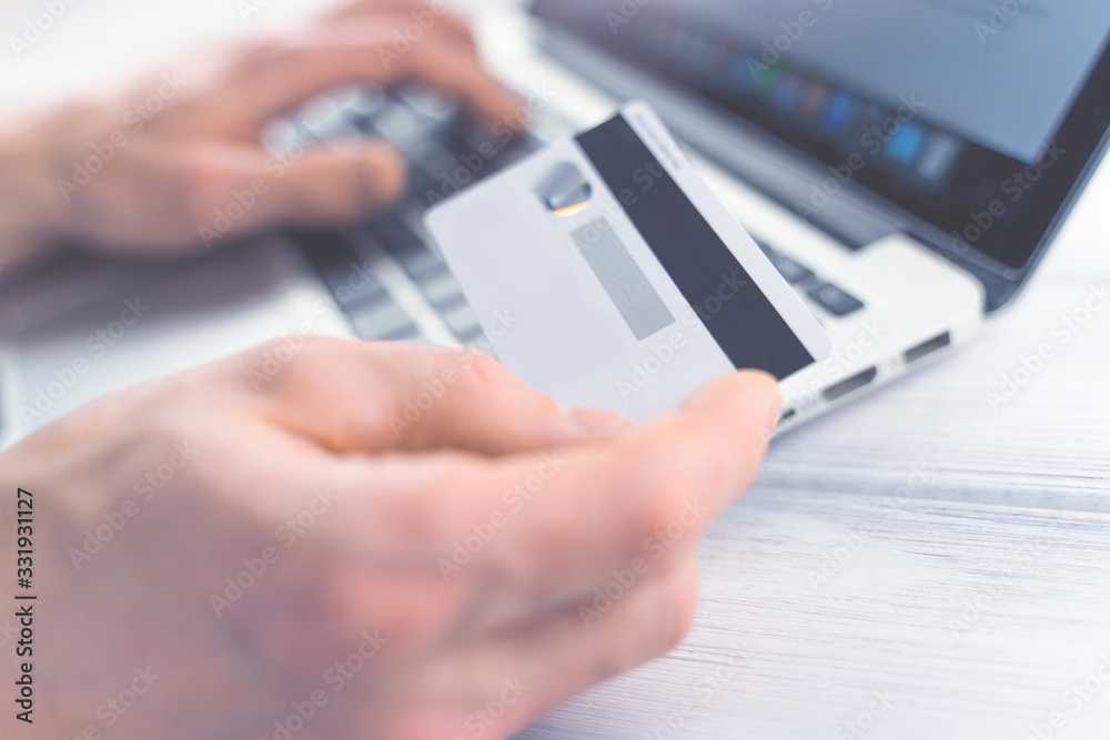 Online shopping concept. Man making online payment. Hands holding bank card. Toned soft focus picture.