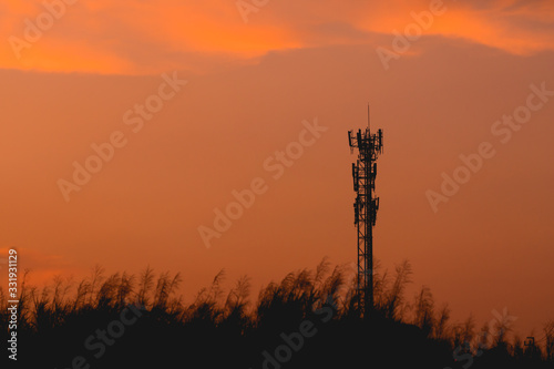 silhouette telecom post on sunset sky background 